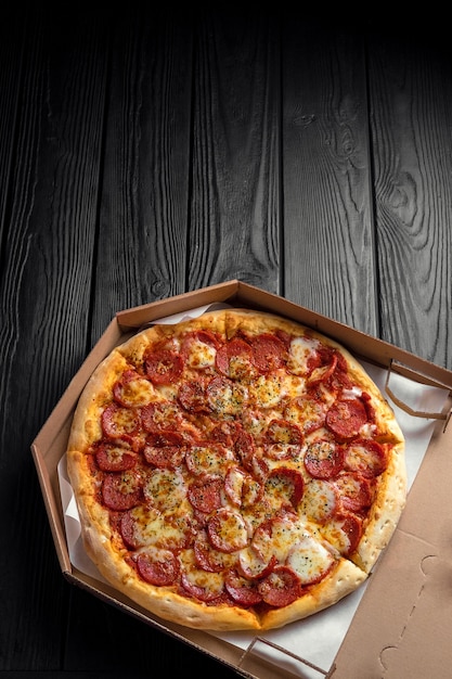 pepperoni pizza on dark black wooden board, top view, place for text, traditional italian pizza