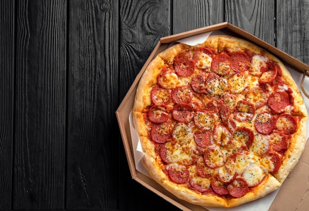 Pizza ai peperoni sul bordo di legno nero scuro