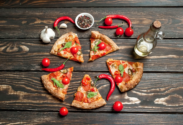 кусочки пиццы пепперони с ингредиентами на фоне дерева