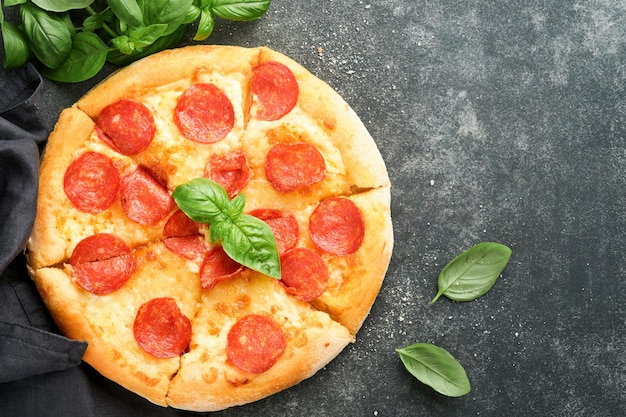 Pepperoni pizza Traditional pepperoni pizza and cooking ingredients tomatoes basil on old concrete texture background table Italian Traditional food Top view Mock up
