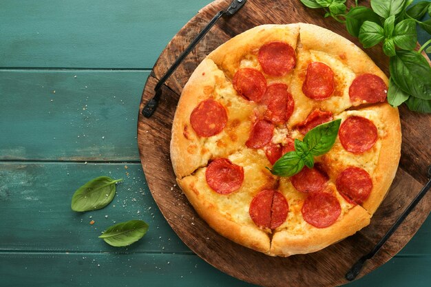 Pepperoni pizza Traditional pepperoni pizza and cooking ingredients tomatoes basil on wooden table backgrounds Italian Traditional food Top view Mock up