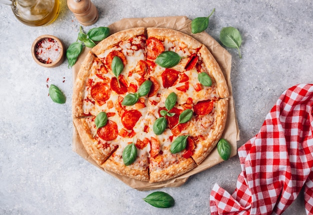灰色の背景にバジルのペパロニのピザ