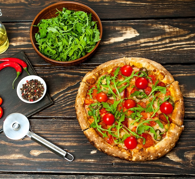 pepperoni pizza with ingredients on wood background