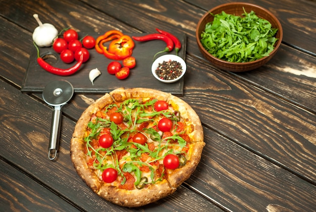 pepperoni pizza with ingredients on wood background