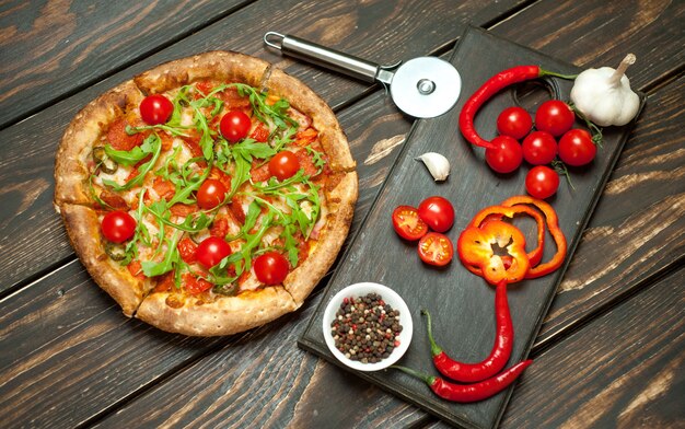 pepperoni pizza with ingredients on wood background
