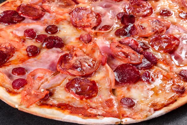 Pepperoni pizza with mozzarella cheese, salami, tomatoes, pepper and spices. Italian cuisine