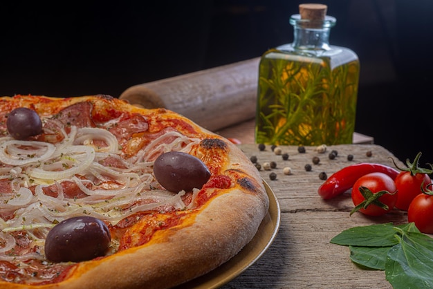 Pepperoni pizza with onions olives and oregano on rustic wooden table