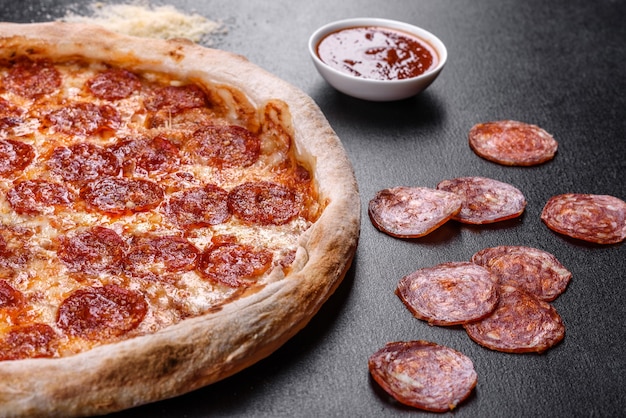 피자 소스, 모짜렐라 치즈, 페퍼로니를 곁들인 페퍼로니 피자. 재료와 함께 테이블에 피자