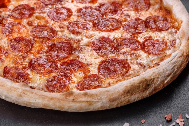 ピザソース、モッツァレラチーズ、ペパロニを添えたペパロニピザ。材料とテーブルの上のピザ