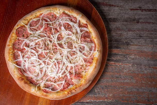 Pepperoni pizza on wooden background Brazilian pizza called pizza de calabresa top view