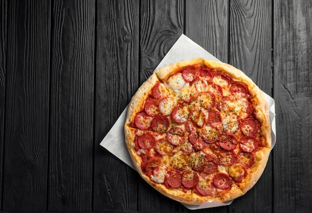 Pepperonipizza op donkere zwarte houten raad