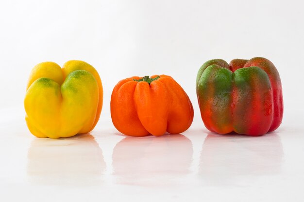 Peppers of different colors with water droplets on a white space