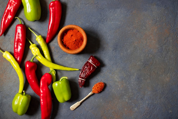 Peppers. Different kinds of pepper. Red peppers, green peppers, hot peppers, dried paprika, paprika powder, jalapeno, chili, spices. Top view. Dark background. Space for text