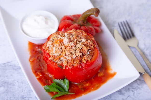 Peppers stuffed with meat, rice and vegetables with tomato sauce and sour cream. A traditional dish. Close-up.