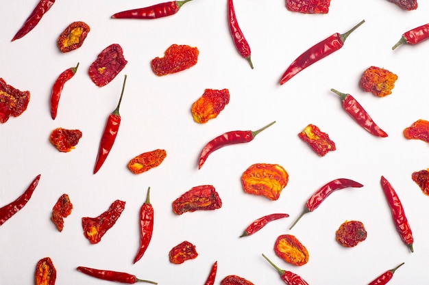 Peppers and tomatoes background dried hot chili peppers and red sundried tomatoes on a white plate spices and vegetables food minimal flat lay background concept high quality photo