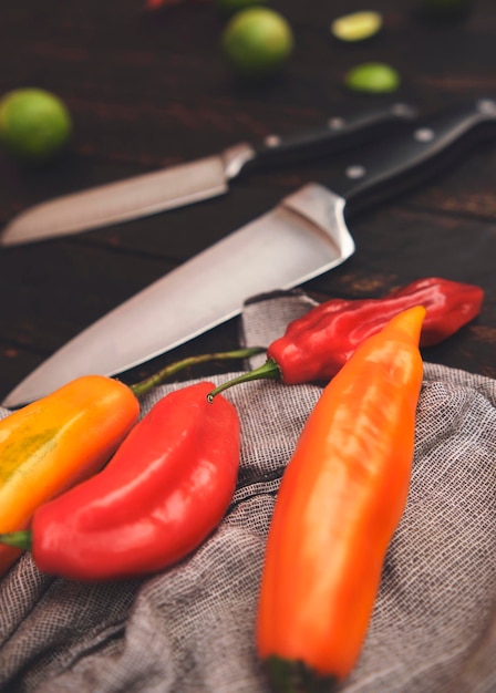 Peppers with other ingredients on wooden table and knife limo pepper