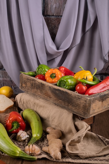 Peppers on a woode tray with zucchini and garlics