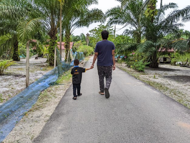 Perak Maleisië 8 augustus 2022 Een volwassen jongen houdt de hand van zijn jongere broer vast tijdens het wandelen in een gebied omringd door oliepalmbomen