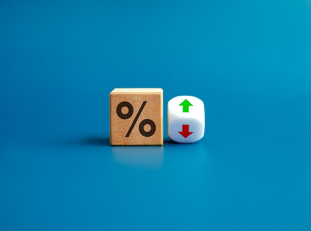 Percentage icon on wooden cube block and up and down arrow symbol on flipping white dice on blue background Interest rate financial stocks ranking GDP percent change money exchange concepts