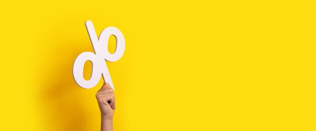 Percentage sign in hand  over yellow background, panoramic image