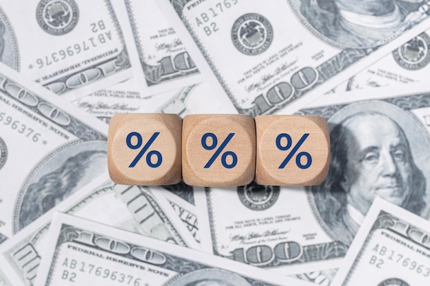 Percentage sign on wooden blocks and US dollar bills background Interest rate concep