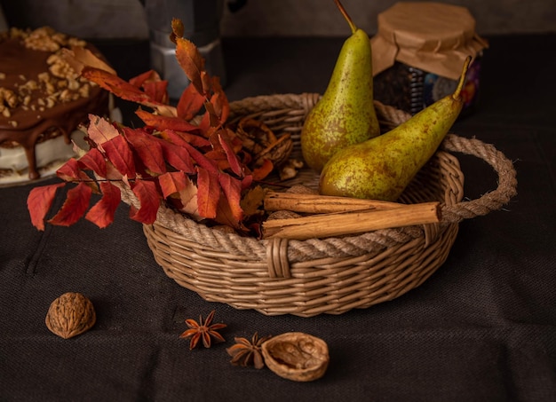 Peren in een mand met herfstlijsterbladkruiden en walnoten