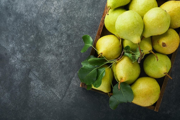 Peren Verse zoete biologische peren met bladeren in houten kist of mand op oude donkergrijze stenen achtergrond Herfstoogst van fruit Bovenaanzicht Voedselachtergrond