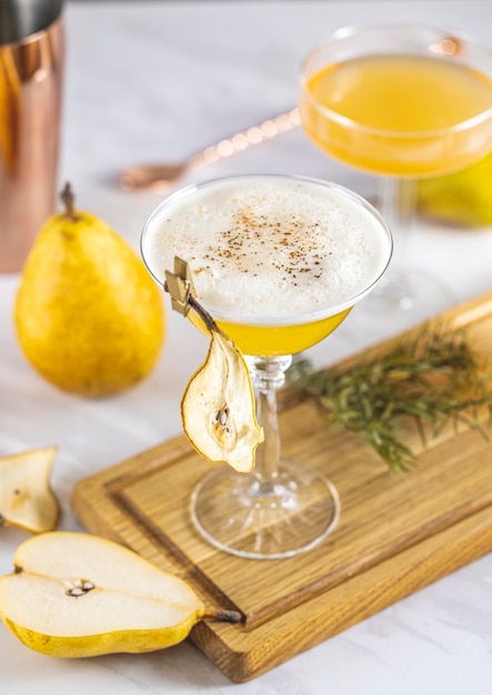 Peren Vlierbloesem Cocktail Champagne coupé glas gevuld met perenpuree cocktail of mocktails omgeven door ingrediënten en bargereedschap