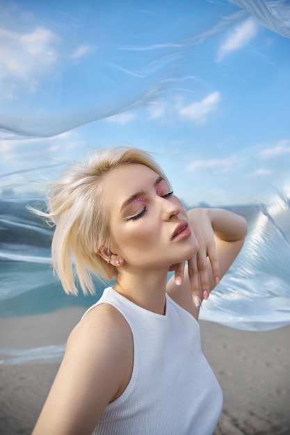 完璧なブロンドの女性の短い髪。ファッションの女性は、晴れた日に自然の中で夏にポーズをとります。赤いネイルマニキュア