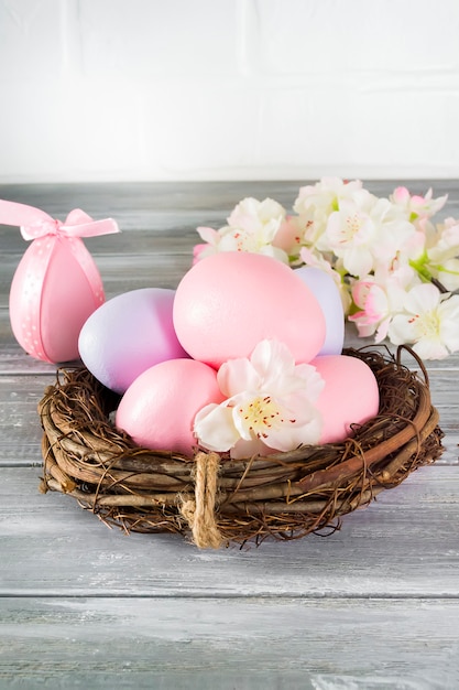 Photo perfect colorful handmade easter eggs in a nest with spring flowers on a wooden gray wall. happy easter