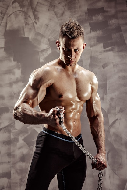 The Perfect male body - Awesome bodybuilder posing. Hold a chain with tattoo