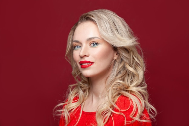 Photo perfect model blonde woman smiling and looking at camera on red background