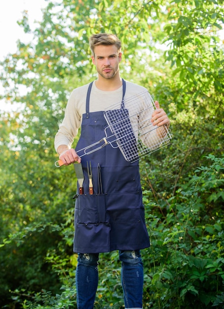 Perfetto uomo da picnic griglia per barbecue gita nel fine settimana in famiglia picnic estivo concetto culinario chef che cucina cibo per barbecue strumenti per arrostire la carne all'aperto picnic utensili da cucina fine settimana per feste all'aperto