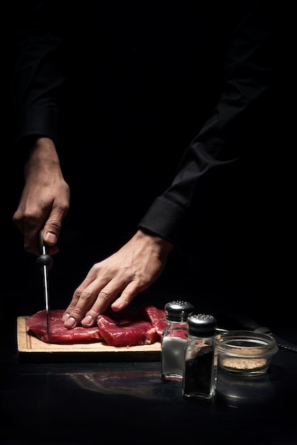 Perfect receipt. Close up of young mans hands chopping meat while cooking and working as a chef in restaurant.