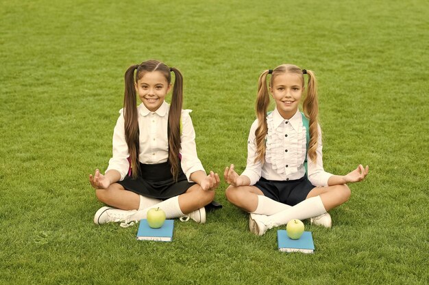 Perfect school children sit on grass with books practice meditation concept