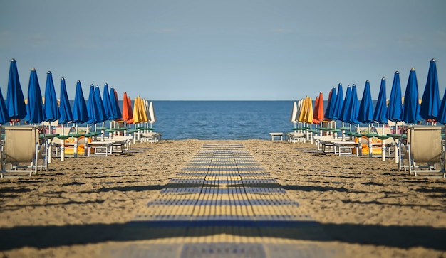 Foto perfect spiegelend en symmetrisch uitzicht op het strand met parasols en ligstoelen van lignano sabbia d'oro in italië. een scène zonder mensen die emoties van rust en vrede geven zoals alleen de zee dat kan.