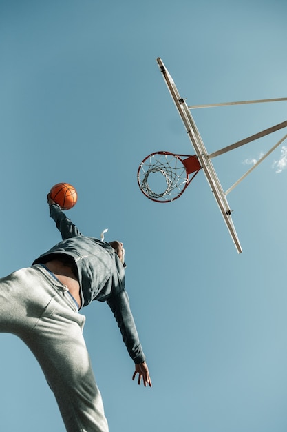 Perfect strike. Low angle of a basketball player jumping while trying to throw the ball into the basket