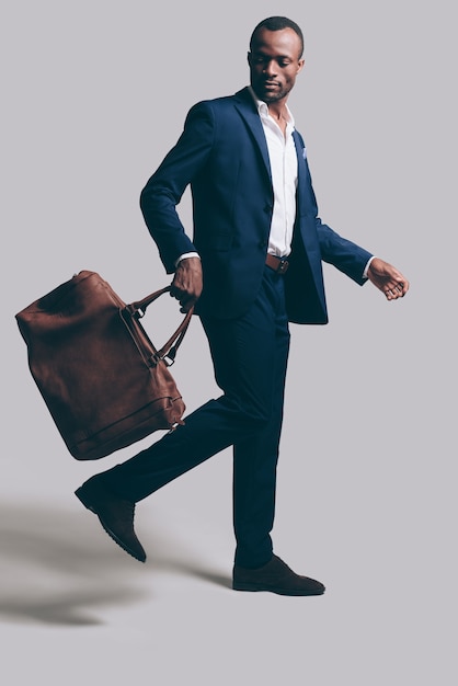 Photo perfect style. full length of handsome young african man carrying brown leather bag while posing