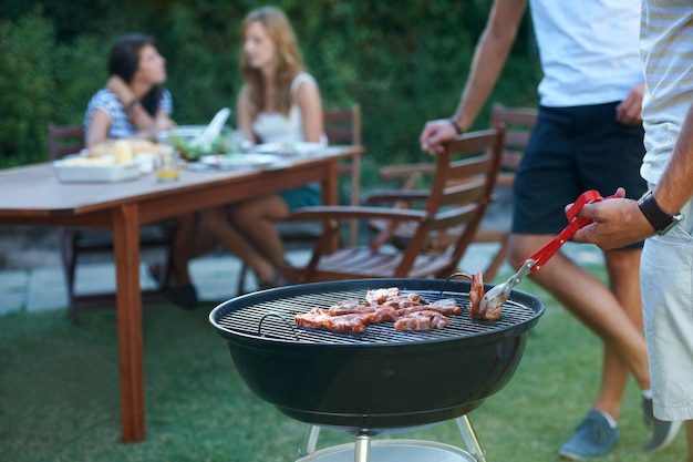 完璧な夏のランチ屋外のグリルで肉をバーベキューする若い男ライフスタイル