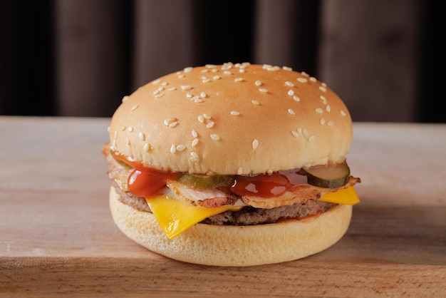 perfect tasty bacon cheeseburger on wooden table on brown background
