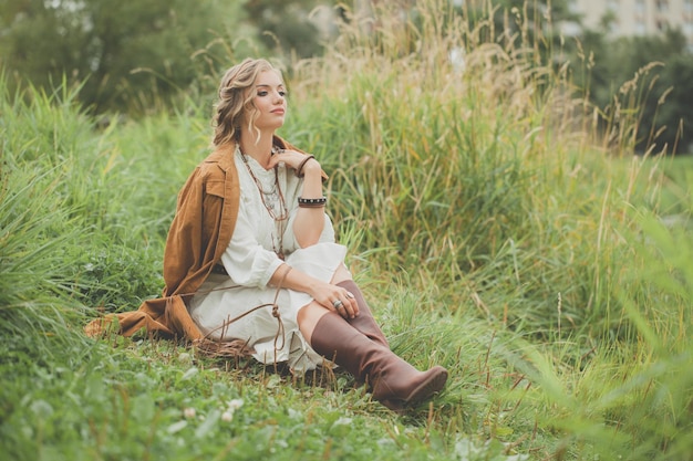 Foto donna perfetta con un vestito in stile boho seduta sull'erba