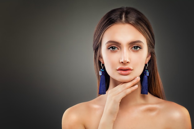 Perfect Woman  Fashion Model with Shiny Makeup and Blue Silky Jewelry Earrings on Background with Copy space