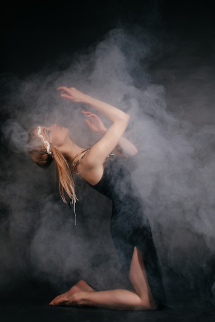 Perfect woman in garb of American Indians in smoke on a gray background