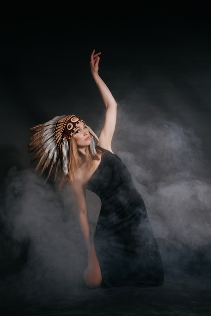 Photo perfect woman in garb of american indians in smoke on gray