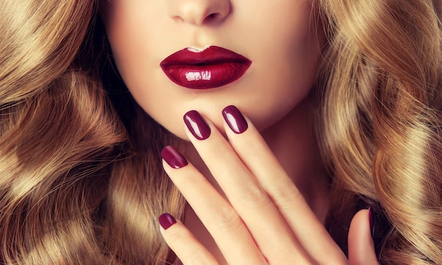 Photo perfect woman lips with ideal shape and colored by bright red lipstick and red manicure on the nails.stylish evening image for young women. fashion makeup and cosmetic.