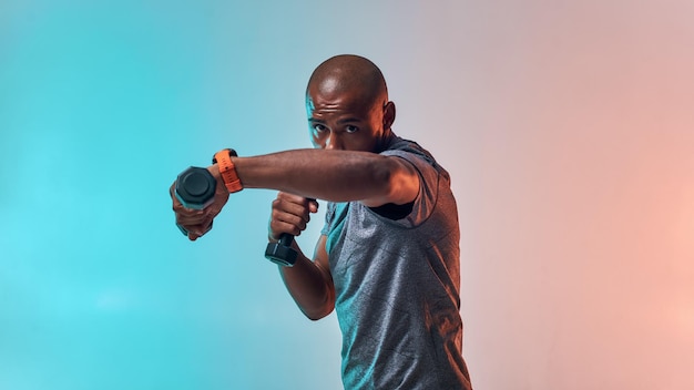 Perfecte biceps gespierde jonge Afrikaanse man die traint met halters terwijl hij tegen kleurrijk staat