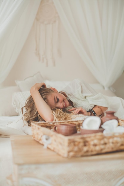 Foto perfecte blonde vrouw ontspant in een hotelkamer in een tropisch resort.