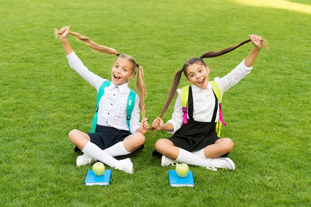 Perfecte schoolkinderen zitten op gras met boeken speelse leerling concept