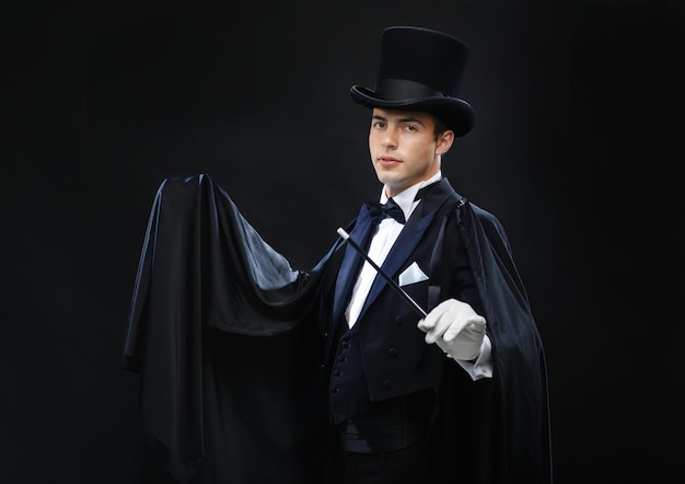 performance, circus, show concept - magician in top hat with magic wand showing trick