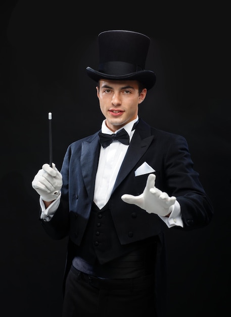 performance, circus, show concept - magician in top hat with magic wand showing trick